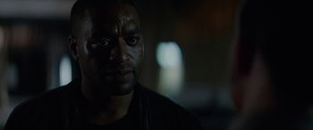 Movie still from “Triple 9” (2016), directed by John Hillcoat – A person wearing a black t - shirt; Close Up shot, Over the shoulder angle
