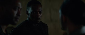 Movie still from “Triple 9” (2016), directed by John Hillcoat – A man in a dark room looking at the camera; Close Up shot, Over the shoulder angle