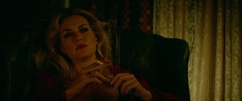 Movie still from “Triple 9” (2016), directed by John Hillcoat – A woman smoking a cigarette while sitting on a couch; Close Up shot, Low angle