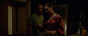 Movie still from “Triple 9” (2016), directed by John Hillcoat – A man and a woman standing next to each other in a kitchen; Medium shot, Over the shoulder angle