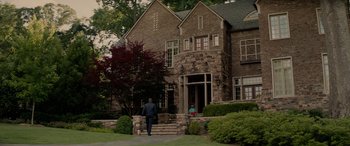 Movie still from “Triple 9” (2016), directed by John Hillcoat – A man walking down the steps of a brick house; Extreme Wide shot, Over the shoulder angle