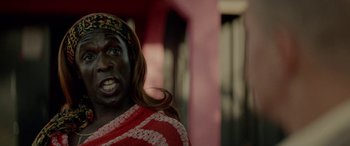 Movie still from “Triple 9” (2016), directed by John Hillcoat – A woman with a red and white striped shirt and a headband; Close Up shot, Over the shoulder angle