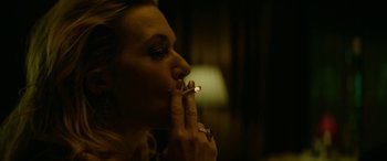 Movie still from “Triple 9” (2016), directed by John Hillcoat – A woman is smoking a cigarette in a dark room; Close Up shot, High angle