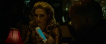 Movie still from “Triple 9” (2016), directed by John Hillcoat – A woman sitting at a table looking at her phone; Close Up shot, Over the shoulder angle