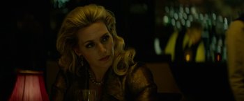 Movie still from “Triple 9” (2016), directed by John Hillcoat – A woman sitting at a table holding a glass of wine; Close Up shot, Over the shoulder angle