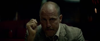 Movie still from “Triple 9” (2016), directed by John Hillcoat – A man in a suit and tie with a goatee; Close Up shot, Low angle