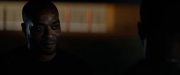 Movie still from “Triple 9” (2016), directed by John Hillcoat – A person in a dark room; Close Up shot, Over the shoulder angle