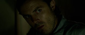 Movie still from “Triple 9” (2016), directed by John Hillcoat – A man's face in the dark; Close Up shot, Over the shoulder angle