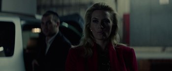 Movie still from “Triple 9” (2016), directed by John Hillcoat – A woman in a red jacket is looking at the camera; Close Up shot, Over the shoulder angle