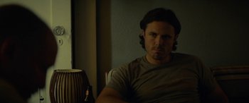 Movie still from “Triple 9” (2016), directed by John Hillcoat – A person sitting in a chair; Close Up shot, Low angle