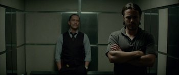 Movie still from “Triple 9” (2016), directed by John Hillcoat – Two men standing next to each other in front of a mirror; Medium shot, Low angle
