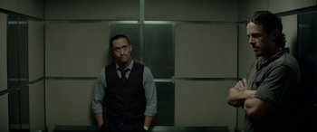 Movie still from “Triple 9” (2016), directed by John Hillcoat – A man standing in front of a wall with his hands in his pockets; Medium shot, Low angle