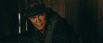 Movie still from “Triple Threat” (2019), directed by Jesse V. Johnson – A man in a camouflage hat and jacket; Close Up shot, Low angle