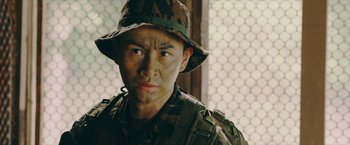 Movie still from “Triple Threat” (2019), directed by Jesse V. Johnson – A man wearing a camouflage hat and uniform; Close Up shot, Low angle