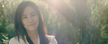Movie still from “Triple Threat” (2019), directed by Jesse V. Johnson – A young woman smiles for the camera in the sunlight; Close Up shot, Low angle