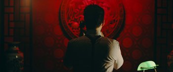 Movie still from “Triple Threat” (2019), directed by Jesse V. Johnson – A man standing in front of a red wall; Medium shot, Low angle
