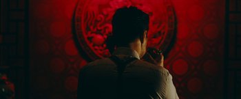 Movie still from “Triple Threat” (2019), directed by Jesse V. Johnson – A man holding a cigarette in his mouth; Medium shot, Over the shoulder angle