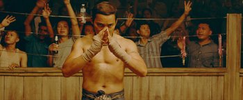 Movie still from “Triple Threat” (2019), directed by Jesse V. Johnson – A man in a boxing ring with his hands wrapped in bandages; Medium shot, Low angle
