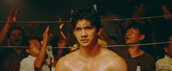 Movie still from “Triple Threat” (2019), directed by Jesse V. Johnson – A young man with wet hair and no shirt in a boxing ring; Close Up shot, Low angle