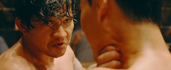 Movie still from “Triple Threat” (2019), directed by Jesse V. Johnson – A man's face as he stares at another man; Close Up shot, Over the shoulder angle