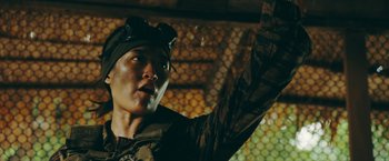 Movie still from “Triple Threat” (2019), directed by Jesse V. Johnson – A man in a military uniform is holding his arm up; Close Up shot, Low angle