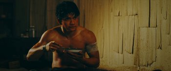 Movie still from “Triple Threat” (2019), directed by Jesse V. Johnson – A shirtless man holding a bowl in his hands; Medium shot, Over the shoulder angle