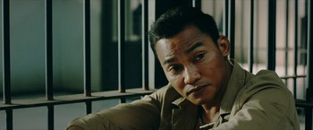 Movie still from “Triple Threat” (2019), directed by Jesse V. Johnson – A person sitting in front of a window; Close Up shot, Over the shoulder angle