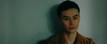 Movie still from “Triple Threat” (2019), directed by Jesse V. Johnson – A person wearing a brown shirt; Close Up shot, Low angle