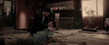 Movie still from “Triple Threat” (2019), directed by Jesse V. Johnson – A man and a woman are sitting on the floor; Medium shot, High angle