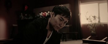 Movie still from “Triple Threat” (2019), directed by Jesse V. Johnson – A man with short black hair is looking at the camera; Close Up shot, Low angle