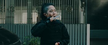 Movie still from “Triple Threat” (2019), directed by Jesse V. Johnson – A woman holding a knife in her mouth; Close Up shot, Low angle