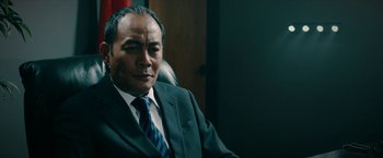 Movie still from “Triple Threat” (2019), directed by Jesse V. Johnson – A person wearing a suit and tie; Close Up shot, Low angle