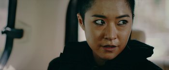 Movie still from “Triple Threat” (2019), directed by Jesse V. Johnson – A person with short black hair; Close Up shot, Over the shoulder angle