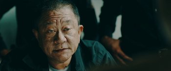 Movie still from “Triple Threat” (2019), directed by Jesse V. Johnson – An older man is looking into the distance; Close Up shot, Over the shoulder angle