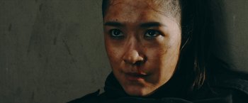 Movie still from “Triple Threat” (2019), directed by Jesse V. Johnson – A person's face in a dark room; Close Up shot, Over the shoulder angle