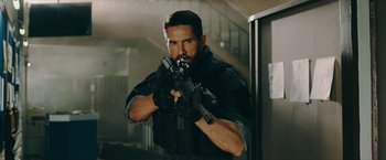 Movie still from “Triple Threat” (2019), directed by Jesse V. Johnson – A man holding a gun in his hands; Medium shot, Over the shoulder angle