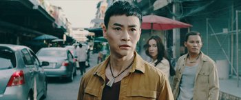 Movie still from “Triple Threat” (2019), directed by Jesse V. Johnson – A young man wearing a brown shirt and a woman in a brown jacket; Close Up shot, Over the shoulder angle