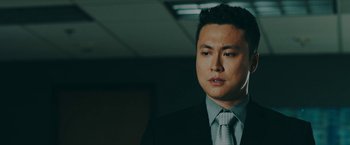 Movie still from “Triple Threat” (2019), directed by Jesse V. Johnson – A person wearing a suit and tie; Close Up shot, Over the shoulder angle