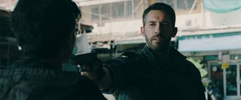 Movie still from “Triple Threat” (2019), directed by Jesse V. Johnson – A man holding a gun in front of another man; Close Up shot, Over the shoulder angle