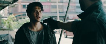 Movie still from “Triple Threat” (2019), directed by Jesse V. Johnson – A man holding a gun up to his face; Close Up shot, Over the shoulder angle