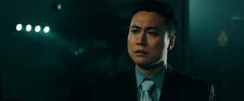 Movie still from “Triple Threat” (2019), directed by Jesse V. Johnson – A person wearing a suit and tie; Close Up shot, Low angle