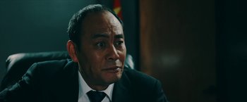 Movie still from “Triple Threat” (2019), directed by Jesse V. Johnson – A person wearing a suit and tie; Close Up shot, Over the shoulder angle