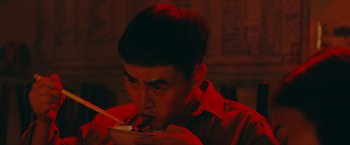 Movie still from “Triple Threat” (2019), directed by Jesse V. Johnson – A man eating a bowl of food in a dark room; Close Up shot, High angle