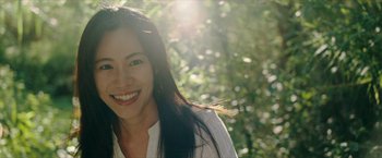 Movie still from “Triple Threat” (2019), directed by Jesse V. Johnson – A woman smiling for the camera in the sunlight; Close Up shot, Low angle