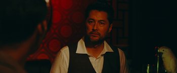 Movie still from “Triple Threat” (2019), directed by Jesse V. Johnson – A person wearing a suit and tie; Close Up shot, Over the shoulder angle