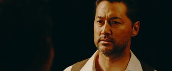 Movie still from “Triple Threat” (2019), directed by Jesse V. Johnson – A person wearing a white shirt; Close Up shot, Over the shoulder angle