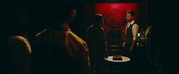 Movie still from “Triple Threat” (2019), directed by Jesse V. Johnson – Two men standing in front of a table with a cake on it; Medium shot, Over the shoulder angle