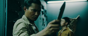 Movie still from “Triple Threat” (2019), directed by Jesse V. Johnson – A man holding a guitar in a room with lights; Close Up shot, Over the shoulder angle