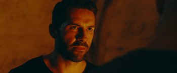 Movie still from “Triple Threat” (2019), directed by Jesse V. Johnson – A person wearing a black t - shirt; Close Up shot, Over the shoulder angle