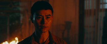 Movie still from “Triple Threat” (2019), directed by Jesse V. Johnson – A man in a brown shirt is looking at the camera; Close Up shot, Over the shoulder angle